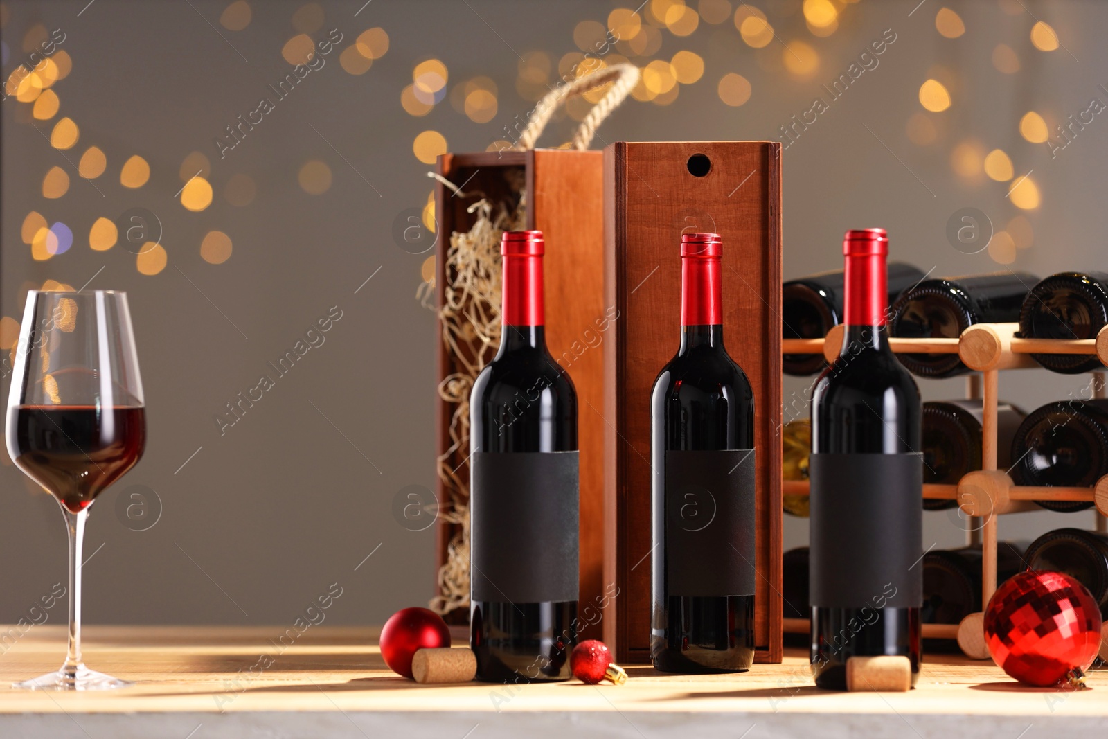 Photo of Bottles of wine, glass, wooden gift boxes, barrel corks and red Christmas balls on table