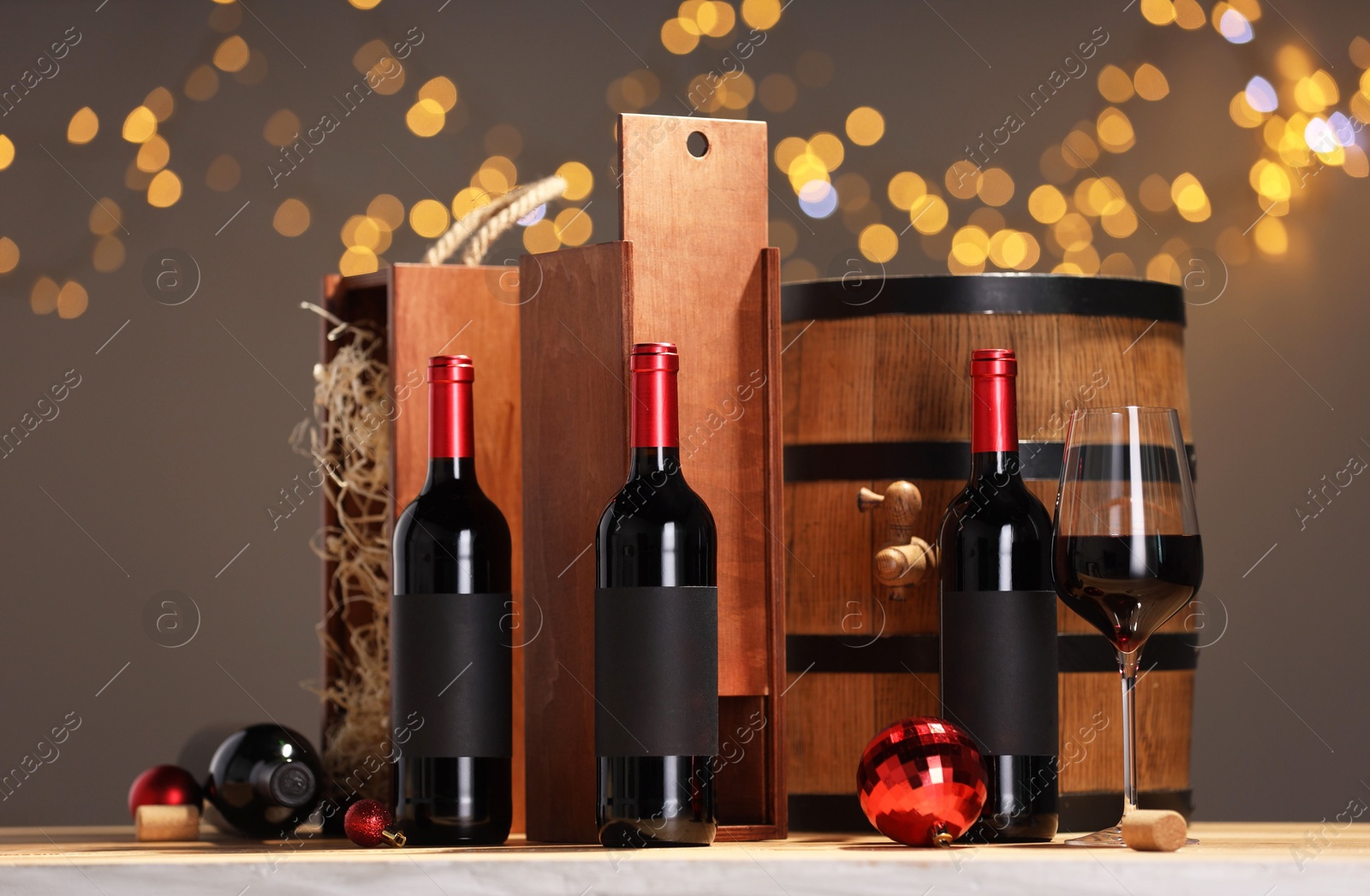 Photo of Bottles of wine, glass, wooden gift boxes, barrel corks and red Christmas balls on table