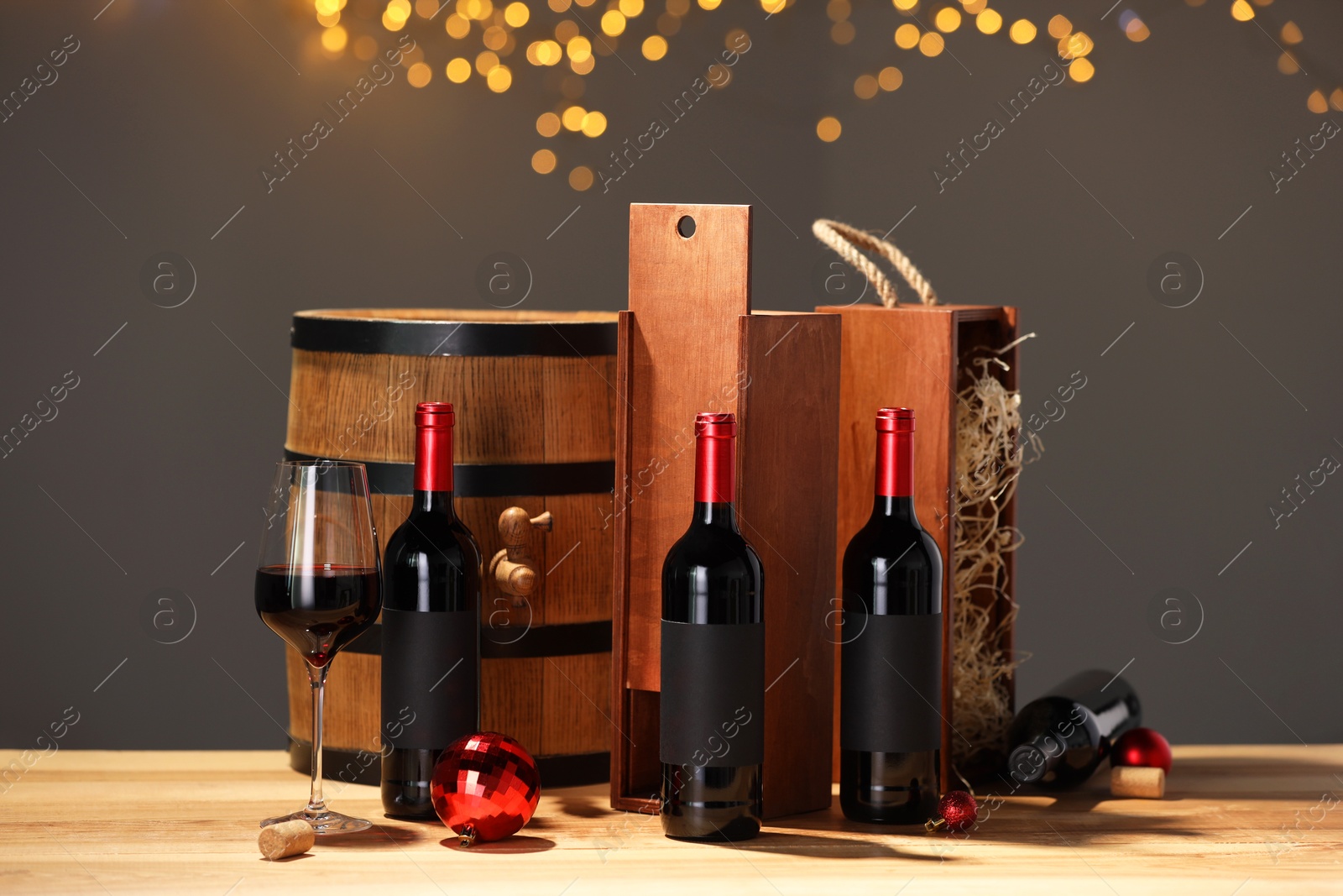 Photo of Bottles of wine, glass, wooden gift boxes, barrel corks and red Christmas balls on table