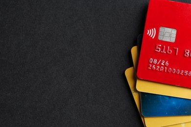 Different credit cards on black background, top view. Space for text