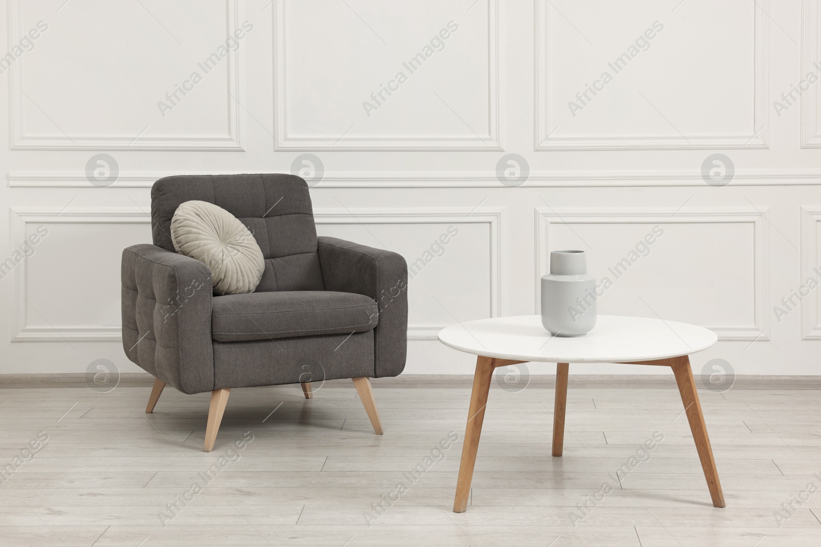 Photo of Soft armchair, coffee table and vase in stylish room