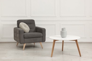 Soft armchair, coffee table and vase in stylish room