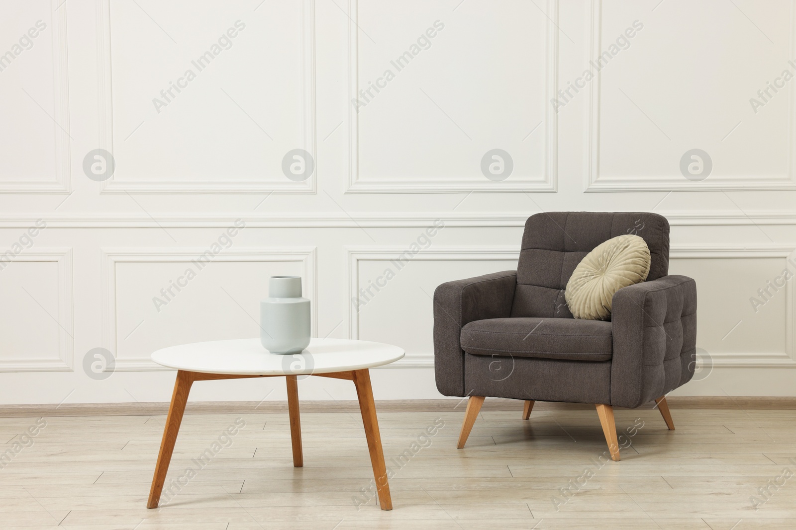 Photo of Soft armchair, coffee table and vase in stylish room