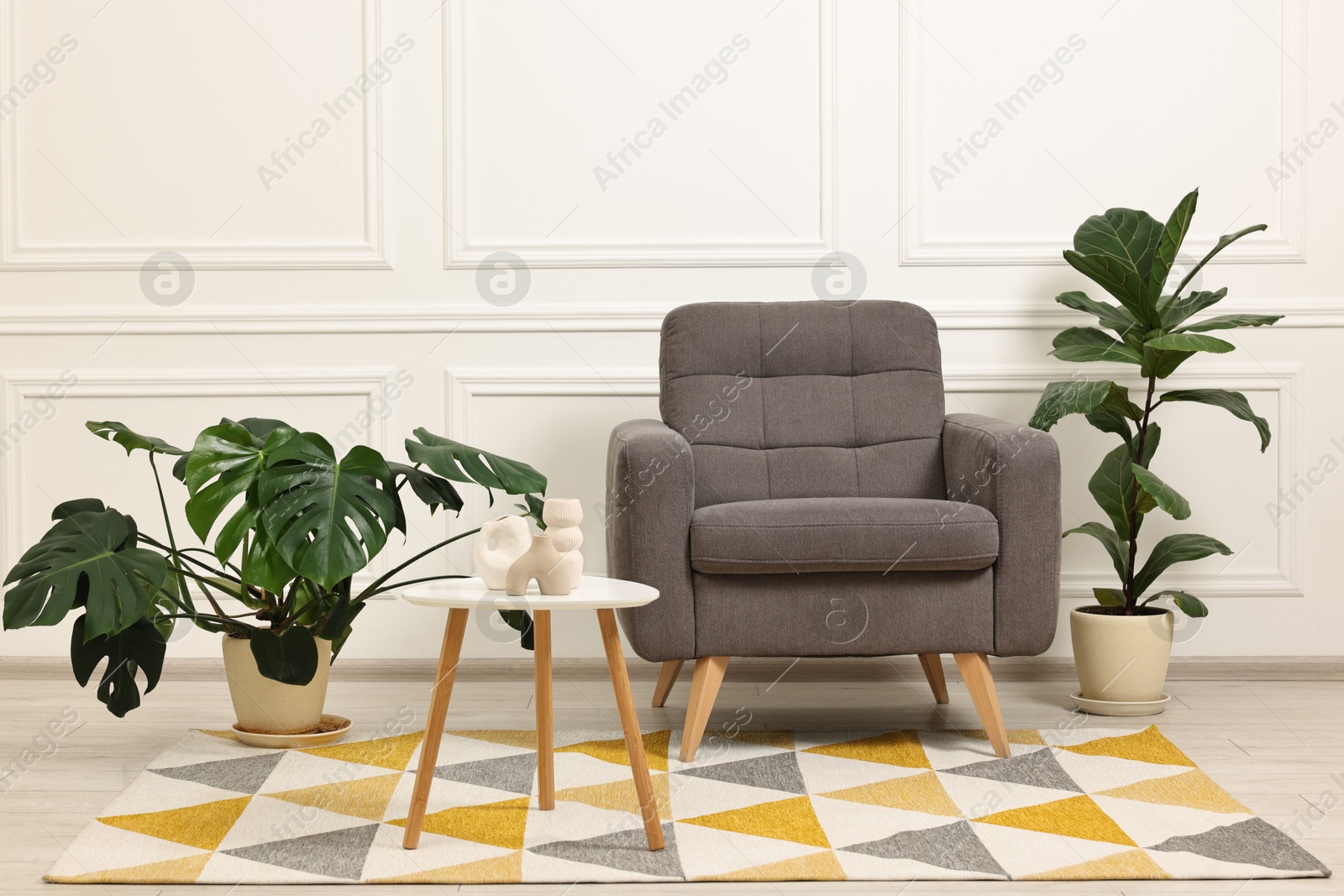 Photo of Soft armchair, coffee table and houseplants in stylish room