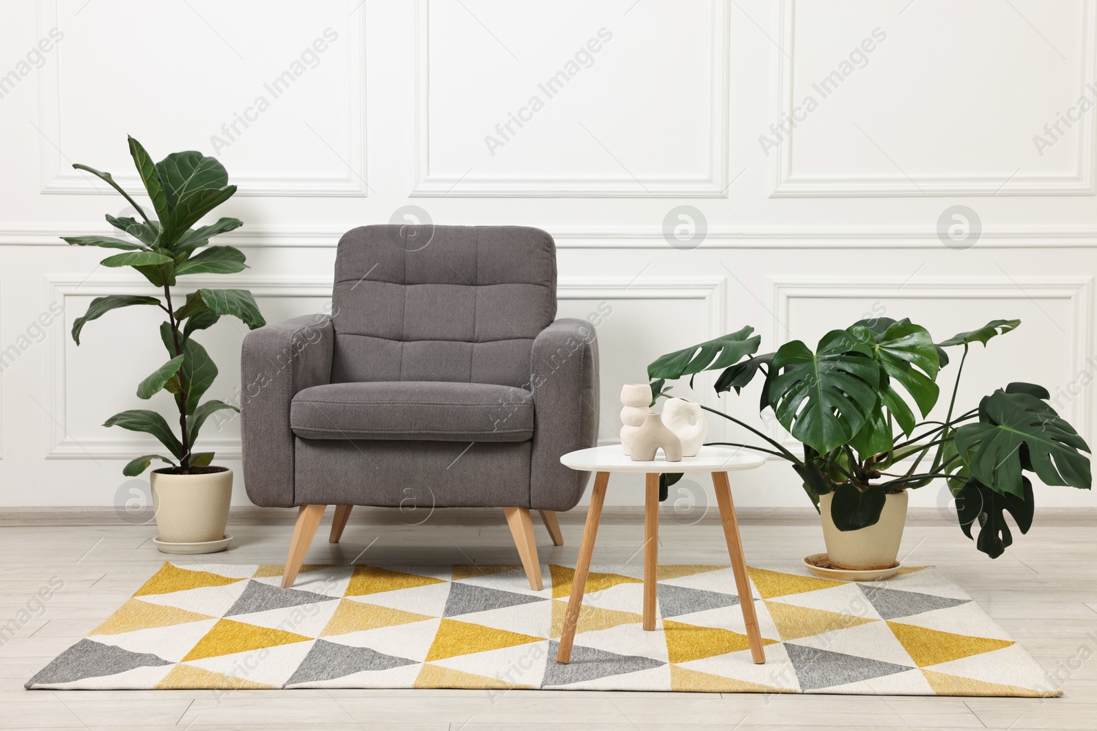 Photo of Soft armchair, coffee table and houseplants in stylish room