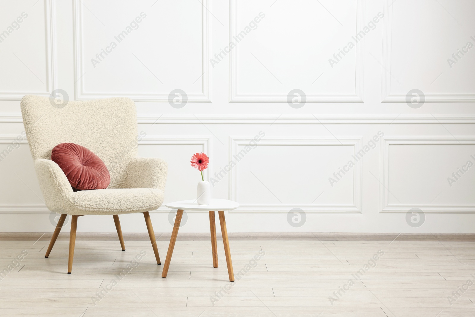 Photo of Soft armchair and coffee table with flower in stylish room. Space for text