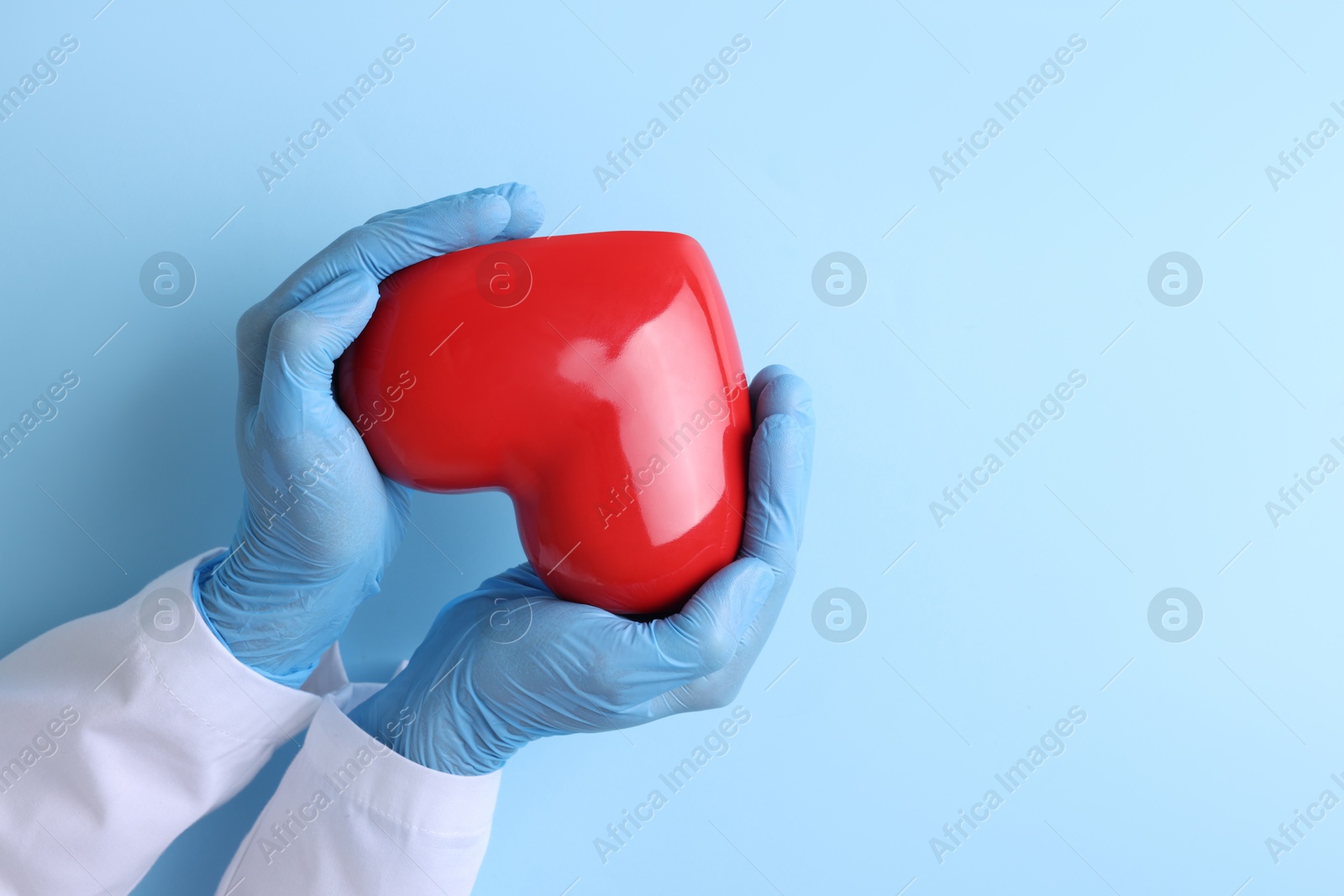 Photo of Doctor holding red heart on light blue background, top view. Space for text