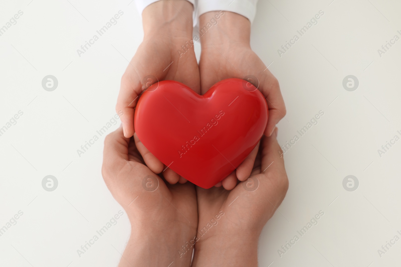 Photo of Doctor and patient holding red heart on white background, top view