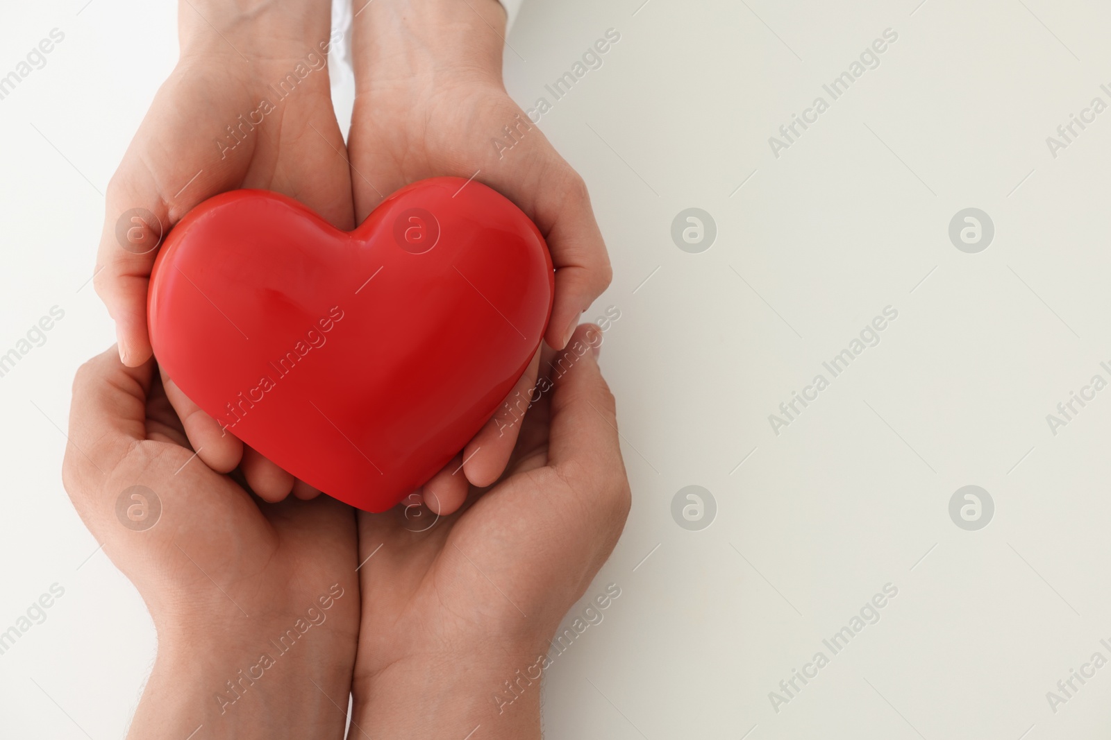 Photo of Doctor and patient holding red heart on white background, top view. Space for text