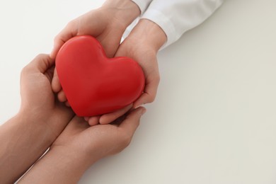 Photo of Doctor and patient holding red heart on white background, top view. Space for text