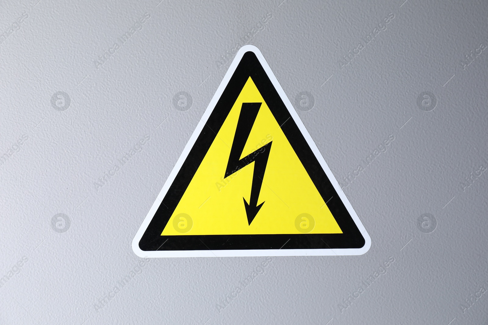 Photo of Yellow danger warning sign on grey wall. Dangerous voltage