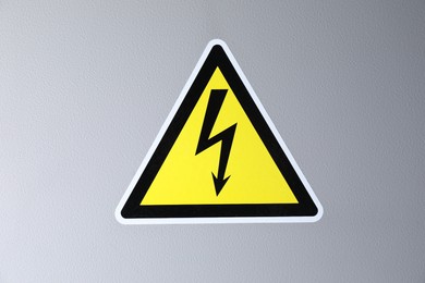 Photo of Yellow danger warning sign on grey wall. Dangerous voltage