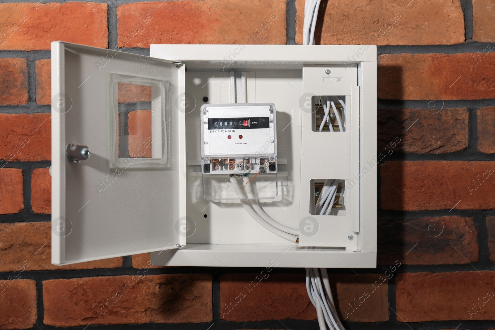 Photo of Electric meter in fuse box on red brick wall. Energy measuring device