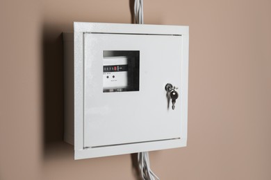 Photo of Electric meter in fuse box on beige wall. Energy measuring device