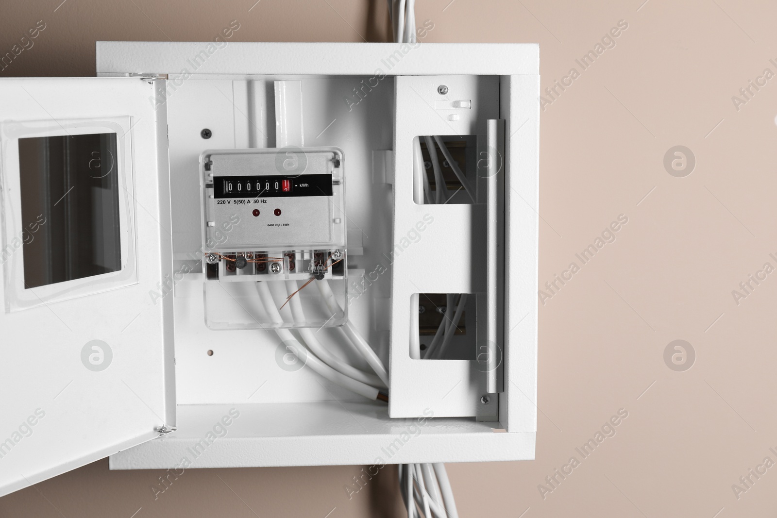 Photo of Electric meter in fuse box on beige wall. Energy measuring device