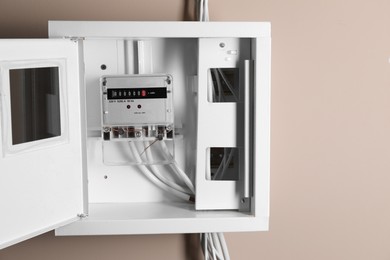 Photo of Electric meter in fuse box on beige wall. Energy measuring device