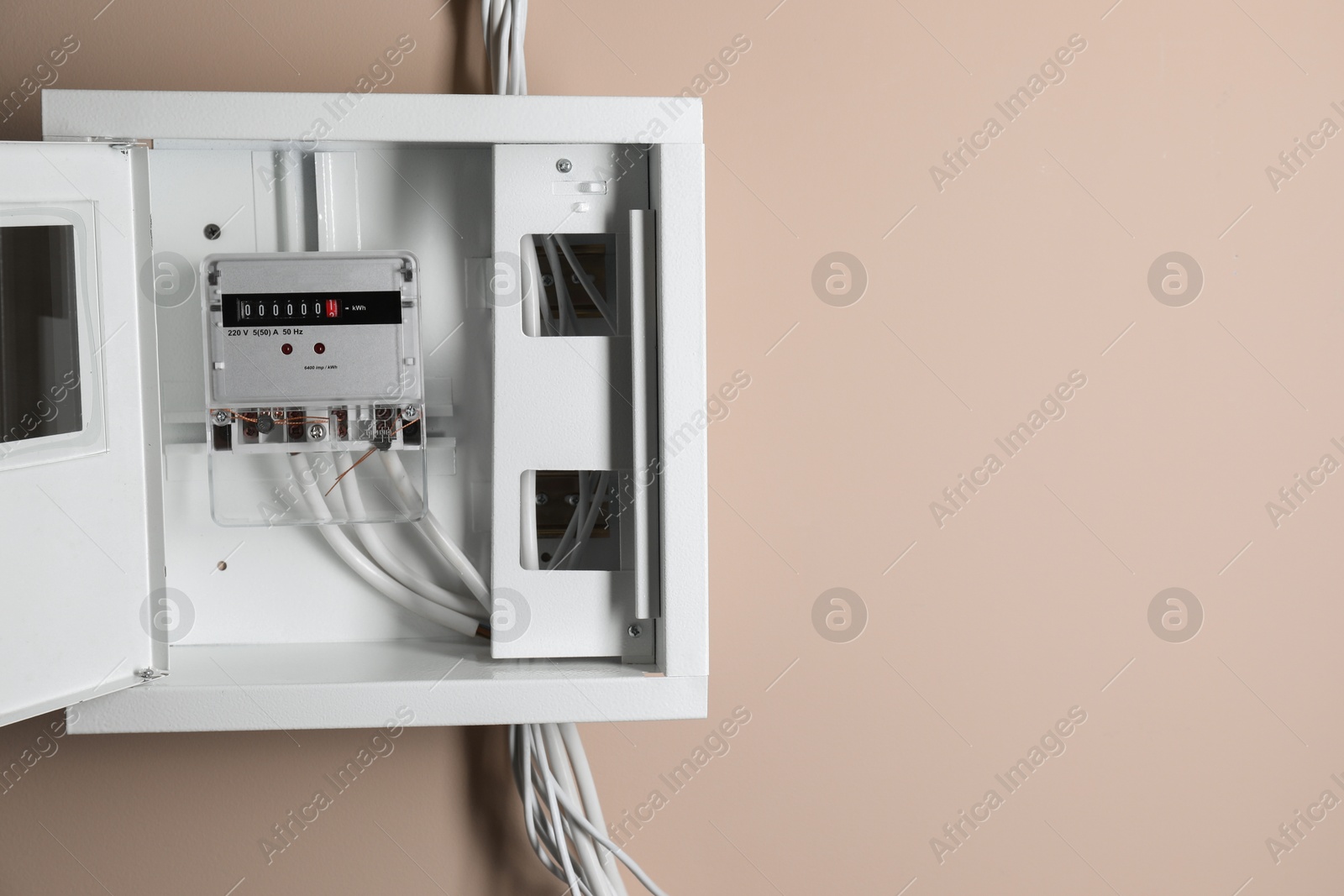 Photo of Electric meter in fuse box on beige wall, space for text. Energy measuring device