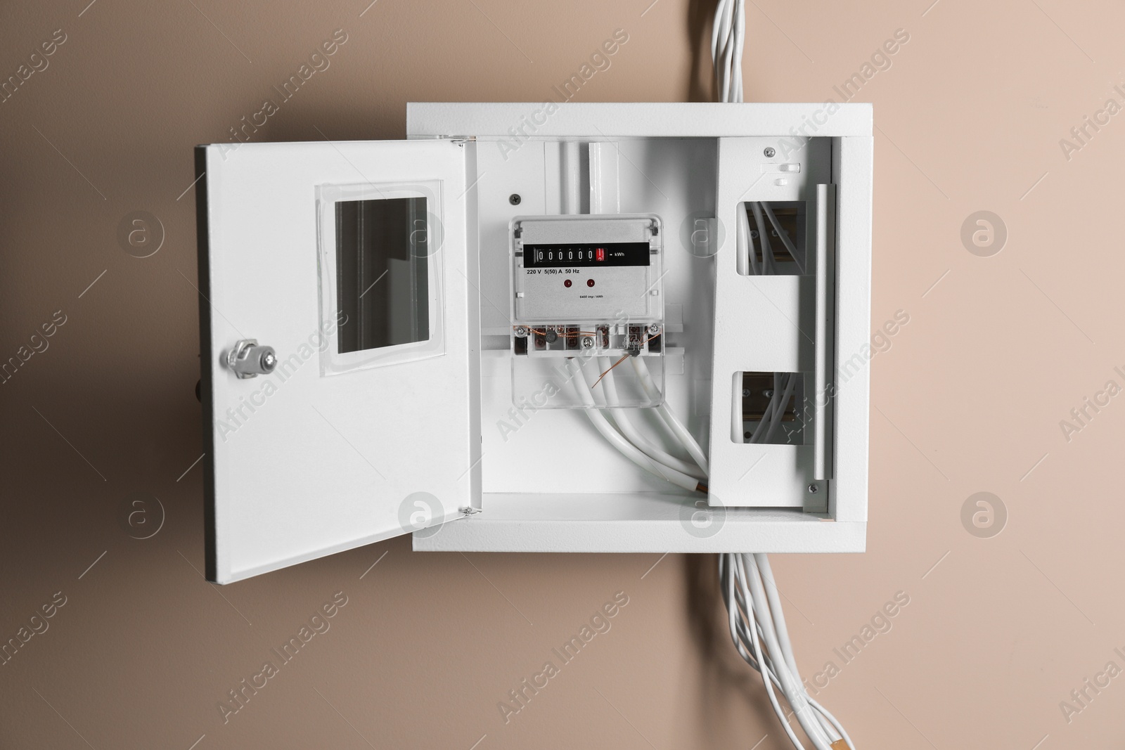 Photo of Electric meter in fuse box on beige wall. Energy measuring device