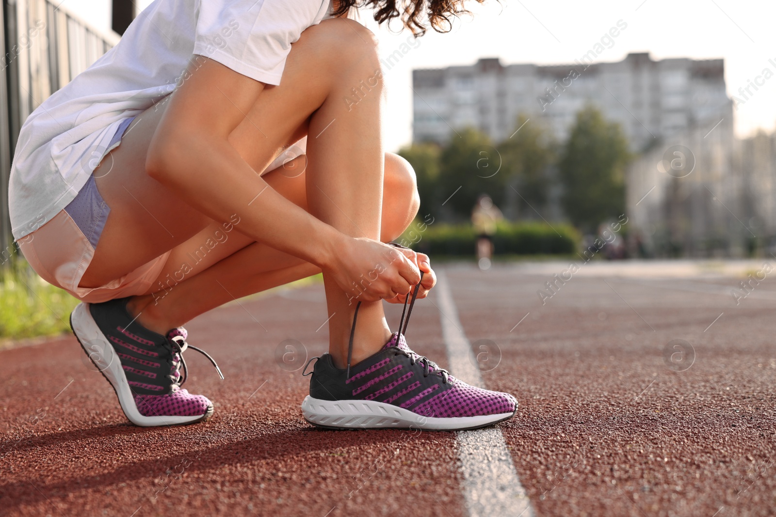 Photo of Woman tying shoelace of sneaker at stadium, closeup. Space for text