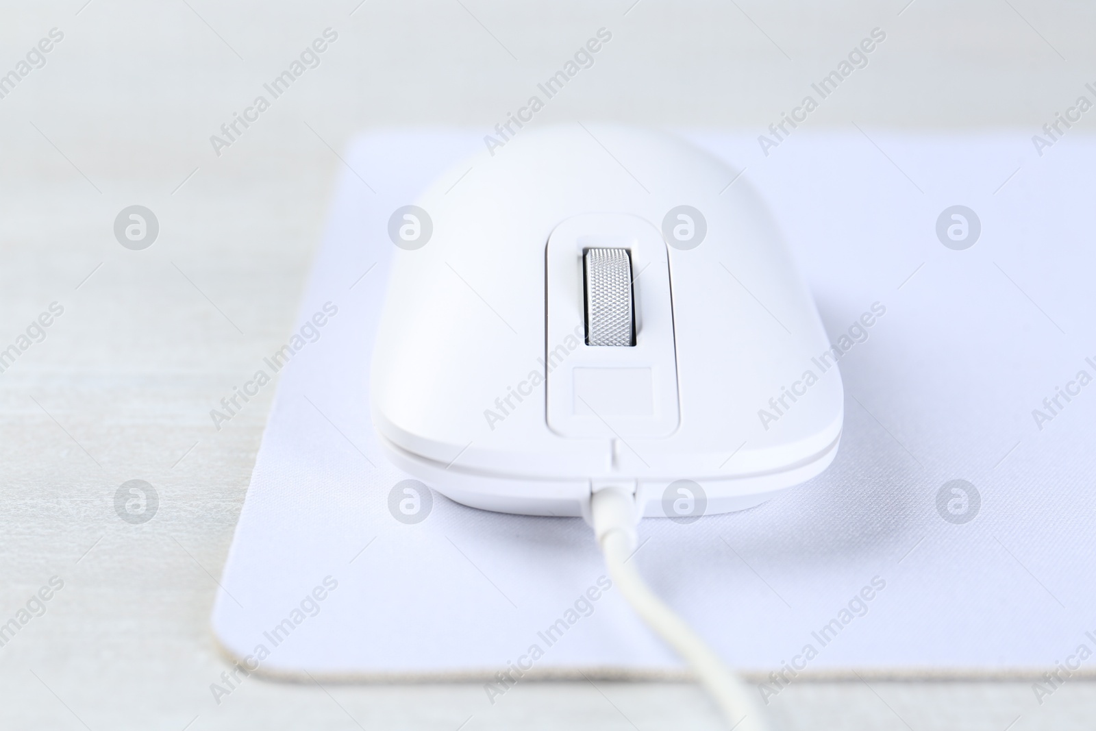 Photo of Computer mouse with mousepad on light table, closeup