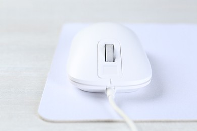 Photo of Computer mouse with mousepad on light table, closeup