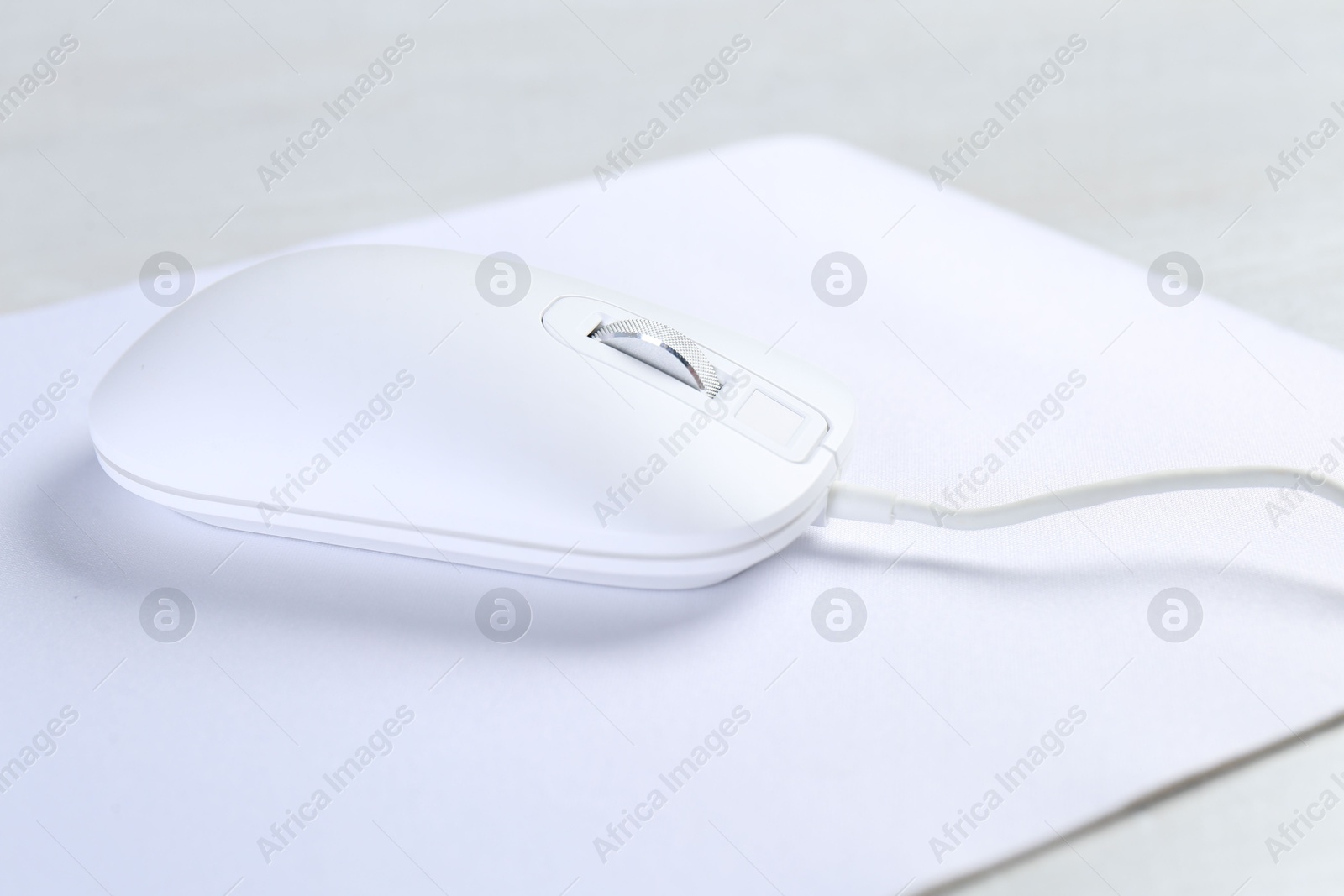 Photo of Computer mouse with mousepad on light table, closeup