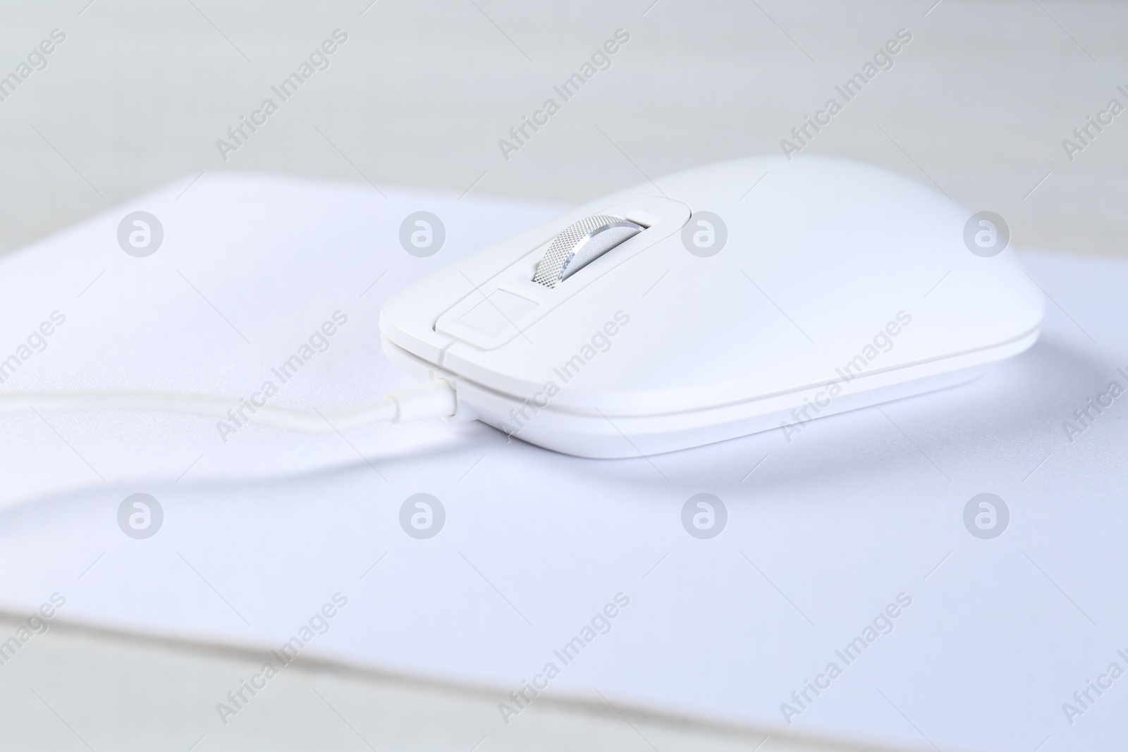 Photo of Computer mouse with mousepad on light table, closeup