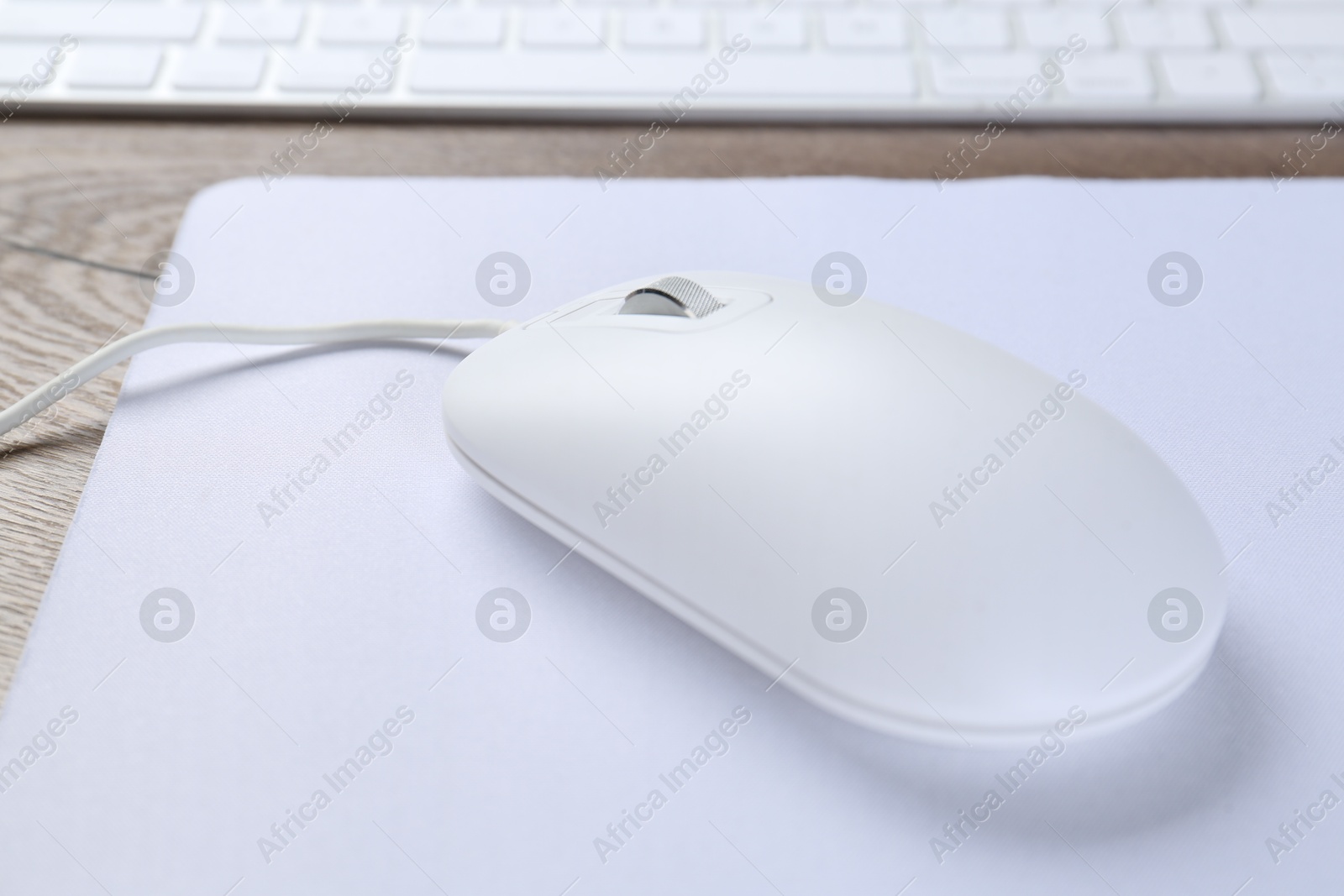 Photo of Computer mouse with mousepad on table, closeup