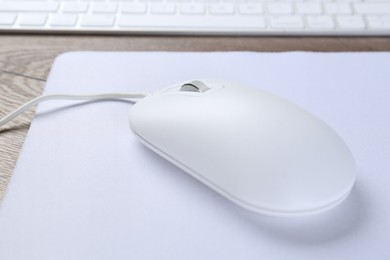 Photo of Computer mouse with mousepad on table, closeup