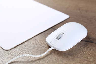 Photo of Computer mouse with mousepad on wooden table