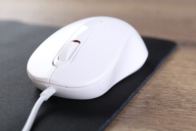 Photo of Computer mouse with mousepad on wooden table, closeup