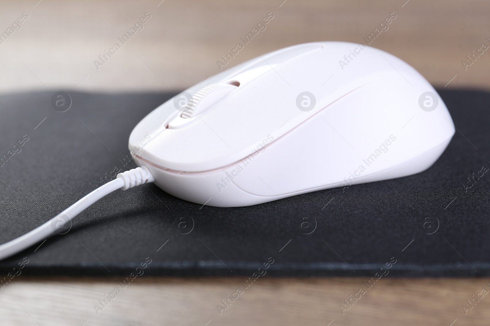 Photo of Computer mouse with mousepad on table, closeup