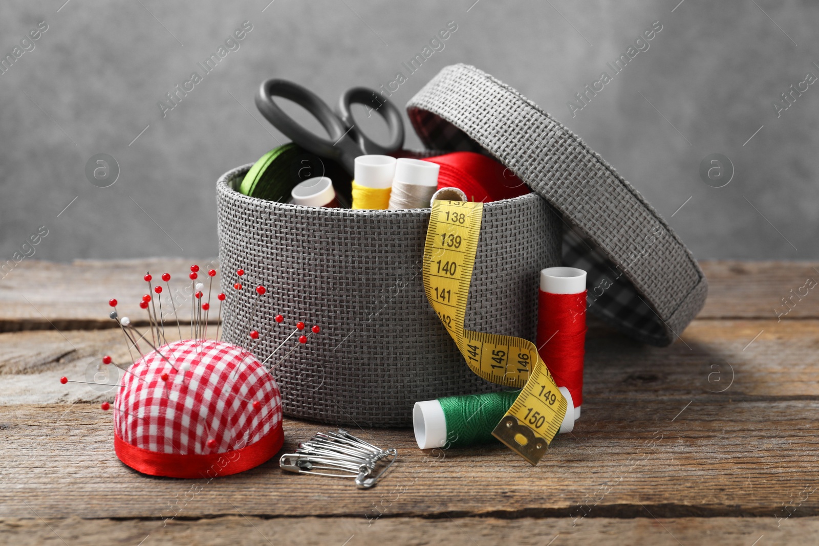 Photo of Checkered pincushion with pins and other sewing tools on wooden table