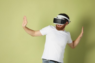 Photo of Man using virtual reality headset on pale green background