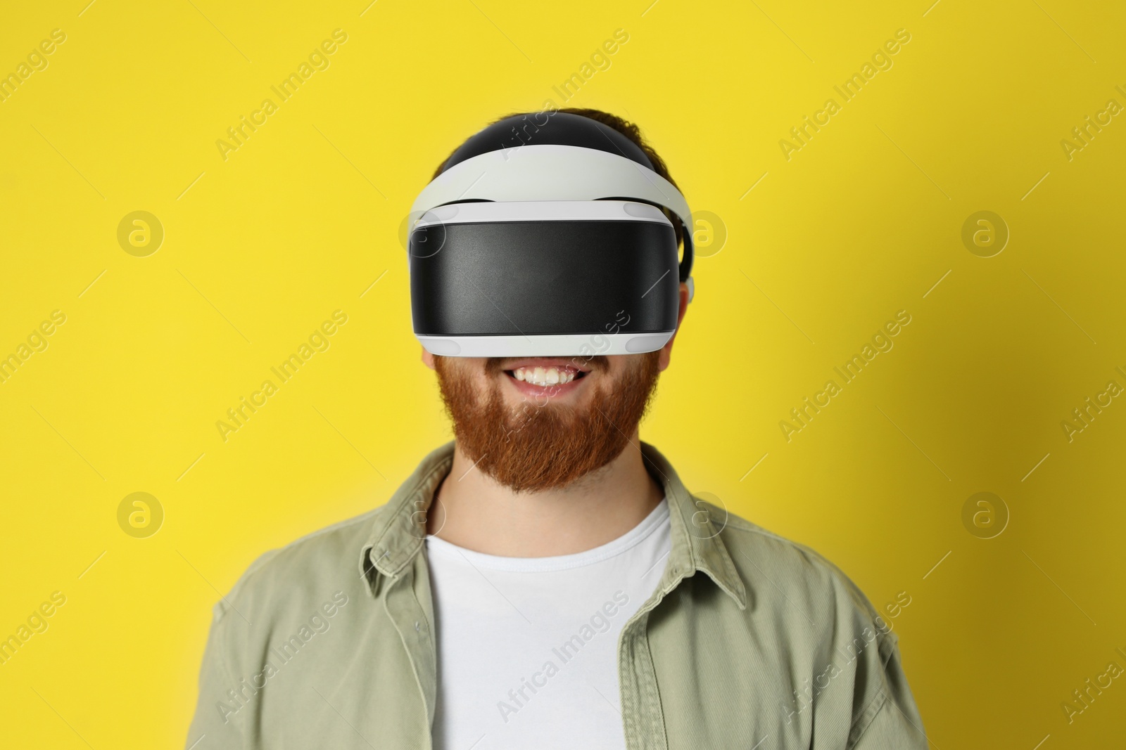 Photo of Smiling man using virtual reality headset on pale yellow background