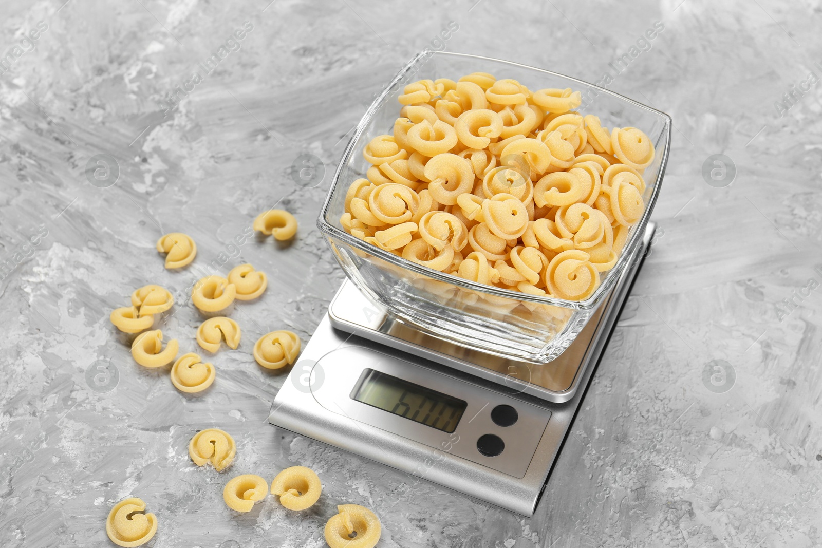 Photo of Kitchen scale with bowl of pasta on grey textured table