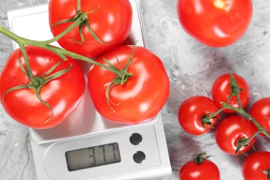 Photo of Kitchen scale with tomatoes on grey textured table, flat lay