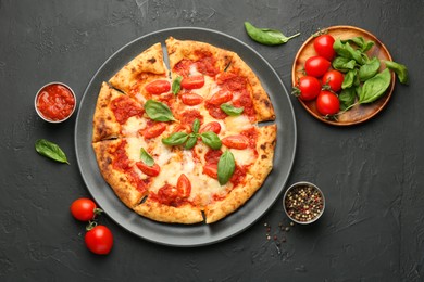 Photo of Delicious Margherita pizza and ingredients on black table, top view