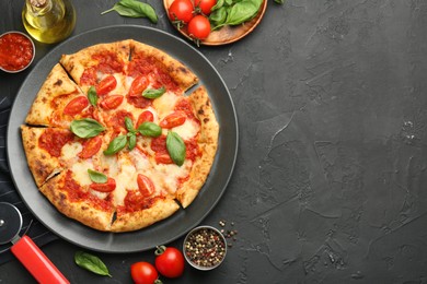 Photo of Delicious Margherita pizza, ingredients and cutter on black table, top view. Space for text