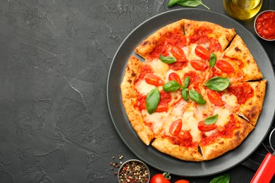 Photo of Delicious Margherita pizza and ingredients on black table, top view. Space for text