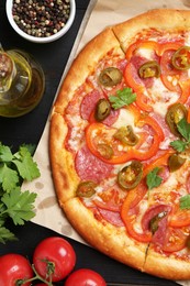 Photo of Delicious pizza Diablo and ingredients on black wooden table, flat lay