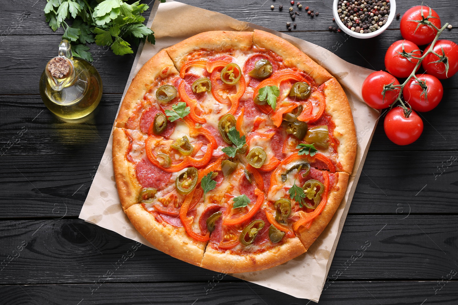 Photo of Delicious pizza Diablo and ingredients on black wooden table, flat lay