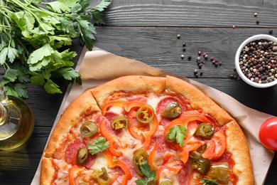 Photo of Delicious pizza Diablo and ingredients on black wooden table, flat lay