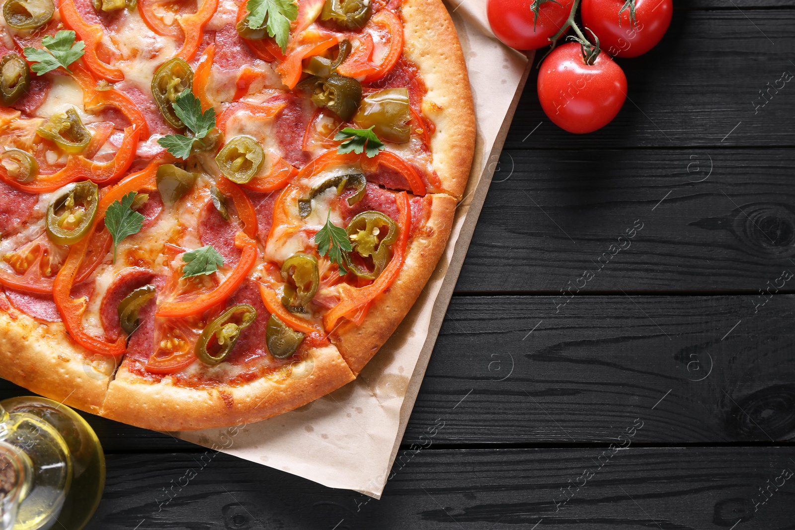 Photo of Delicious pizza Diablo and ingredients on black wooden table, flat lay. Space for text