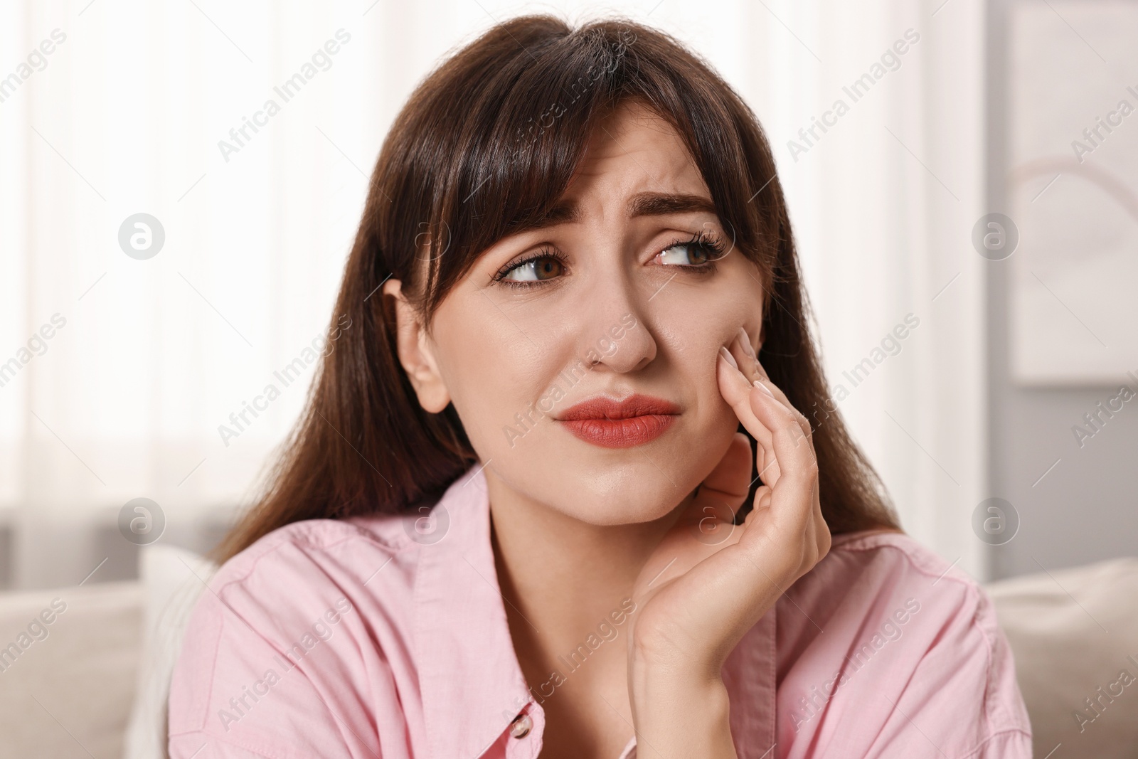 Photo of Upset young woman suffering from toothache indoors