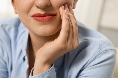 Photo of Woman suffering from toothache indoors, closeup view