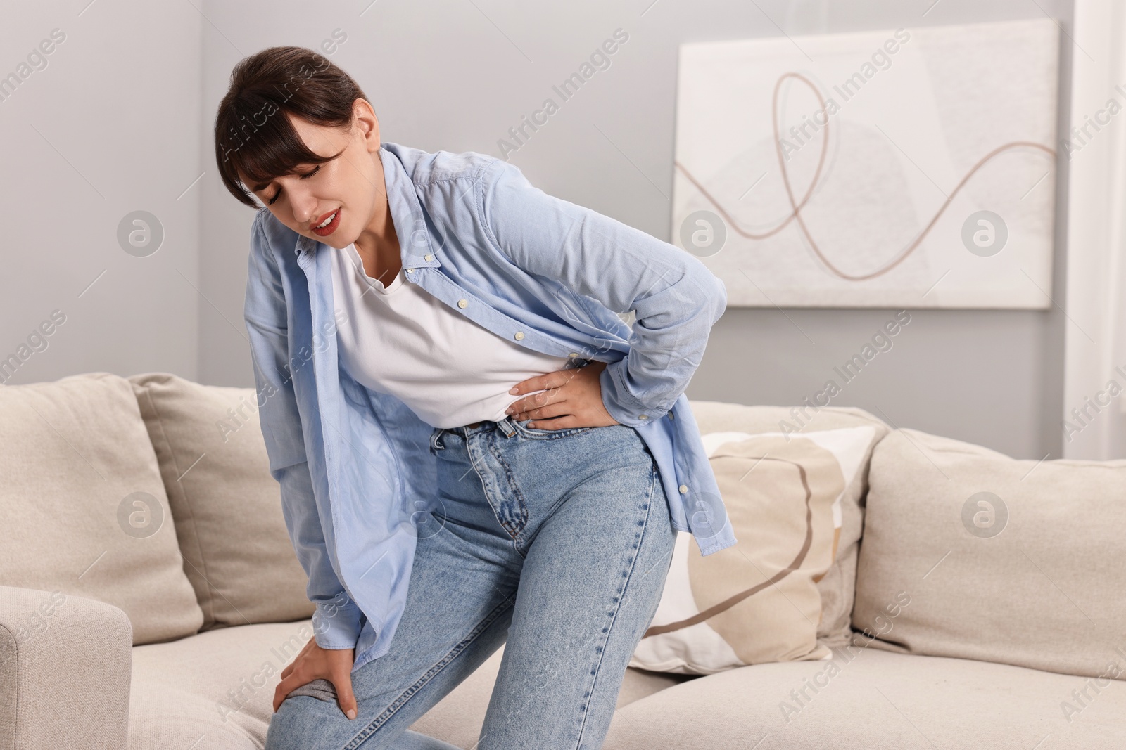 Photo of Upset woman suffering from hip joint pain at home