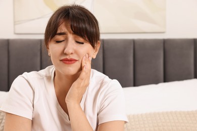 Photo of Upset young woman suffering from toothache indoors, space for text