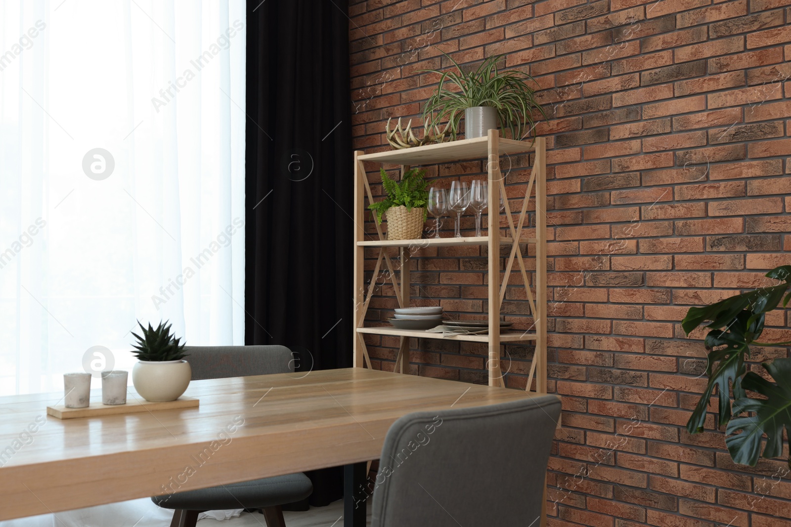 Photo of Shelving unit, table, chairs, green houseplants and elegant curtain in room. Interior design