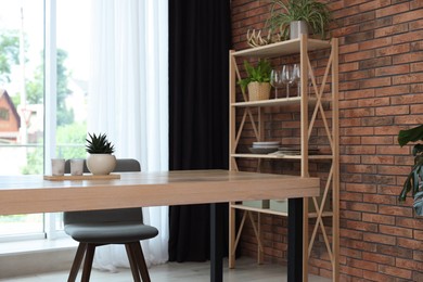 Photo of Shelving unit, table, chair, green houseplants and elegant curtain in room. Interior design